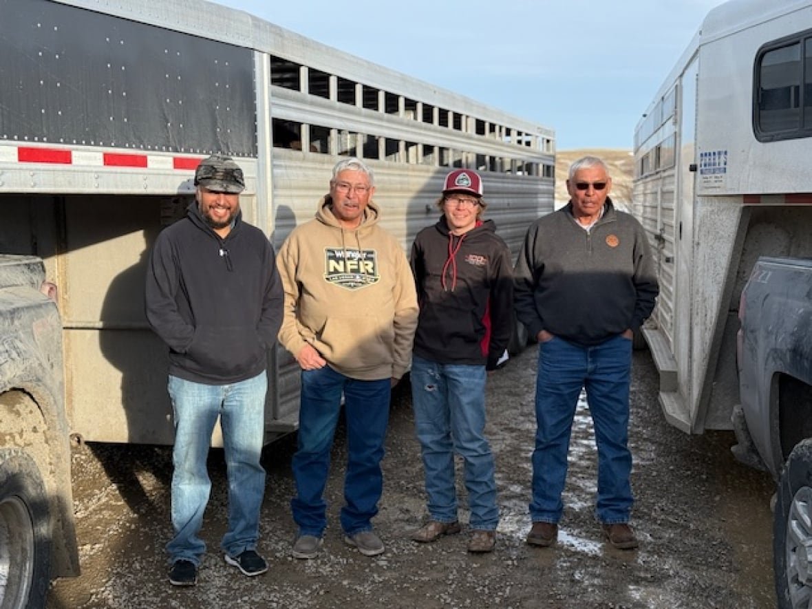 blackfeet-nation-members Four men pose in front of a horse trailer.
