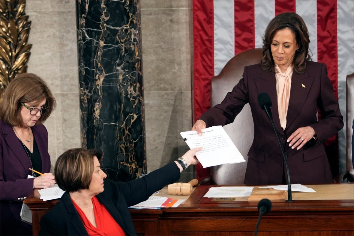 congress-electoral-college-1 Kamala Harris handing paper across a desk.