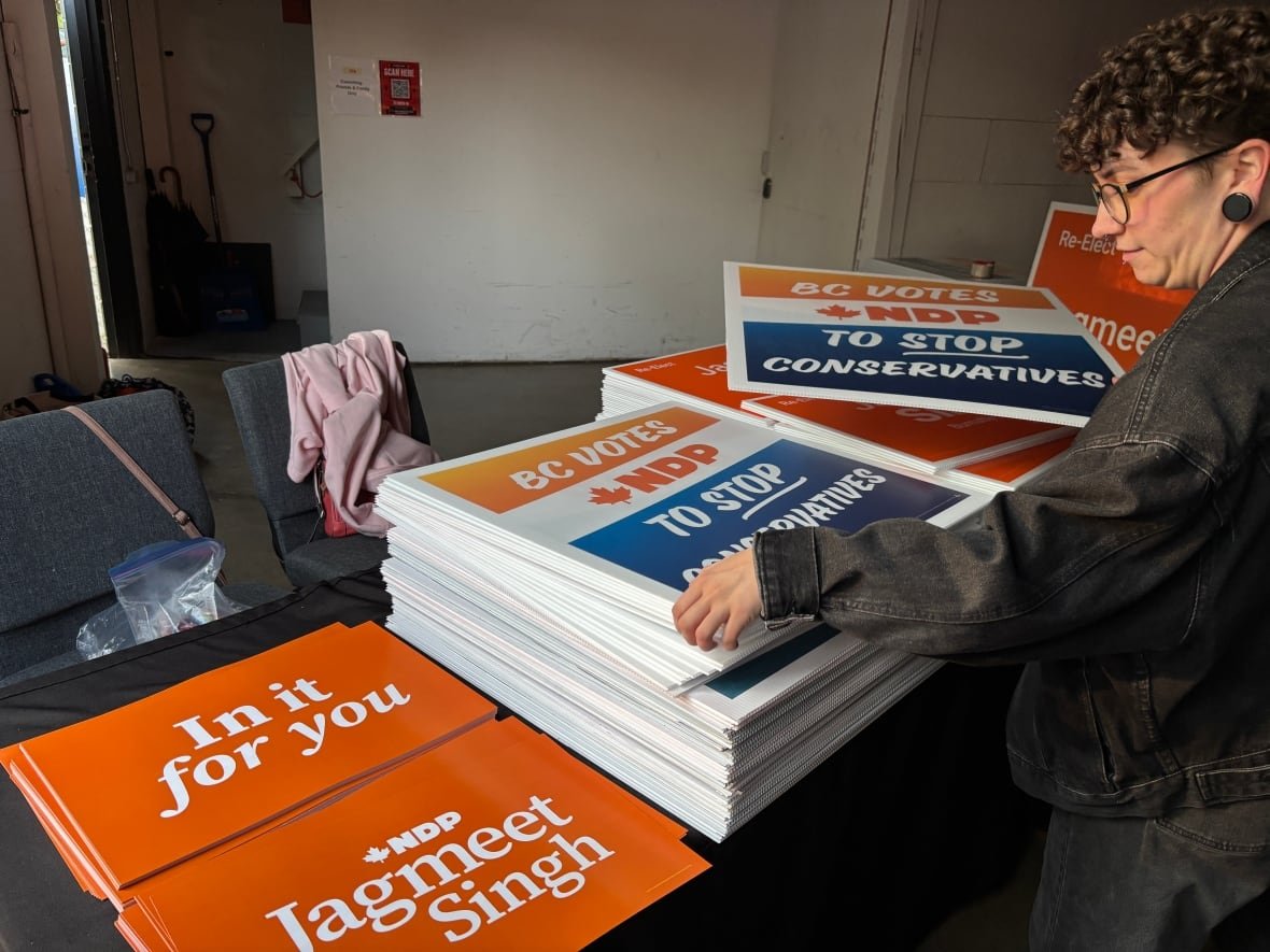 ndp-signs A person looks at election signs on a table.