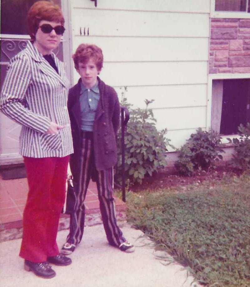 A vintage photograph of a woman and a young boy standing in front of a house door