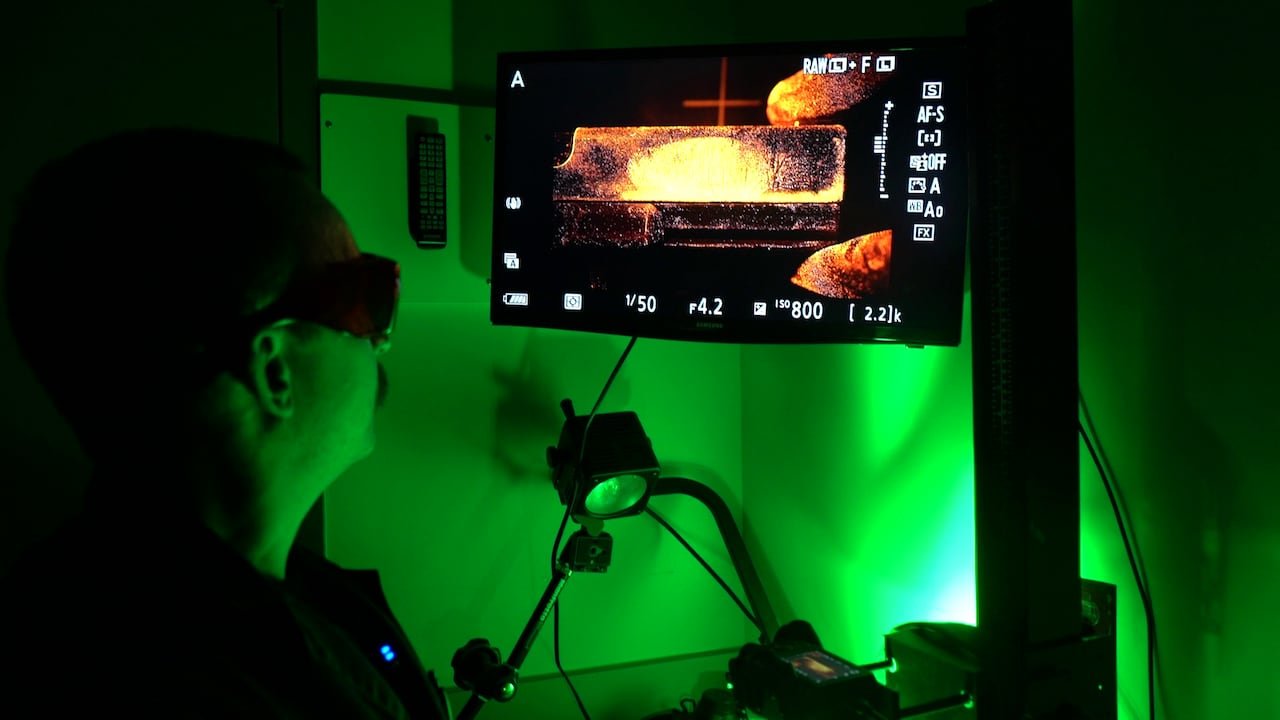 Walsh shines a laser on the part of the gun that he dusted for prints, revealing an image of a fingerprint on a monitor in the lab.