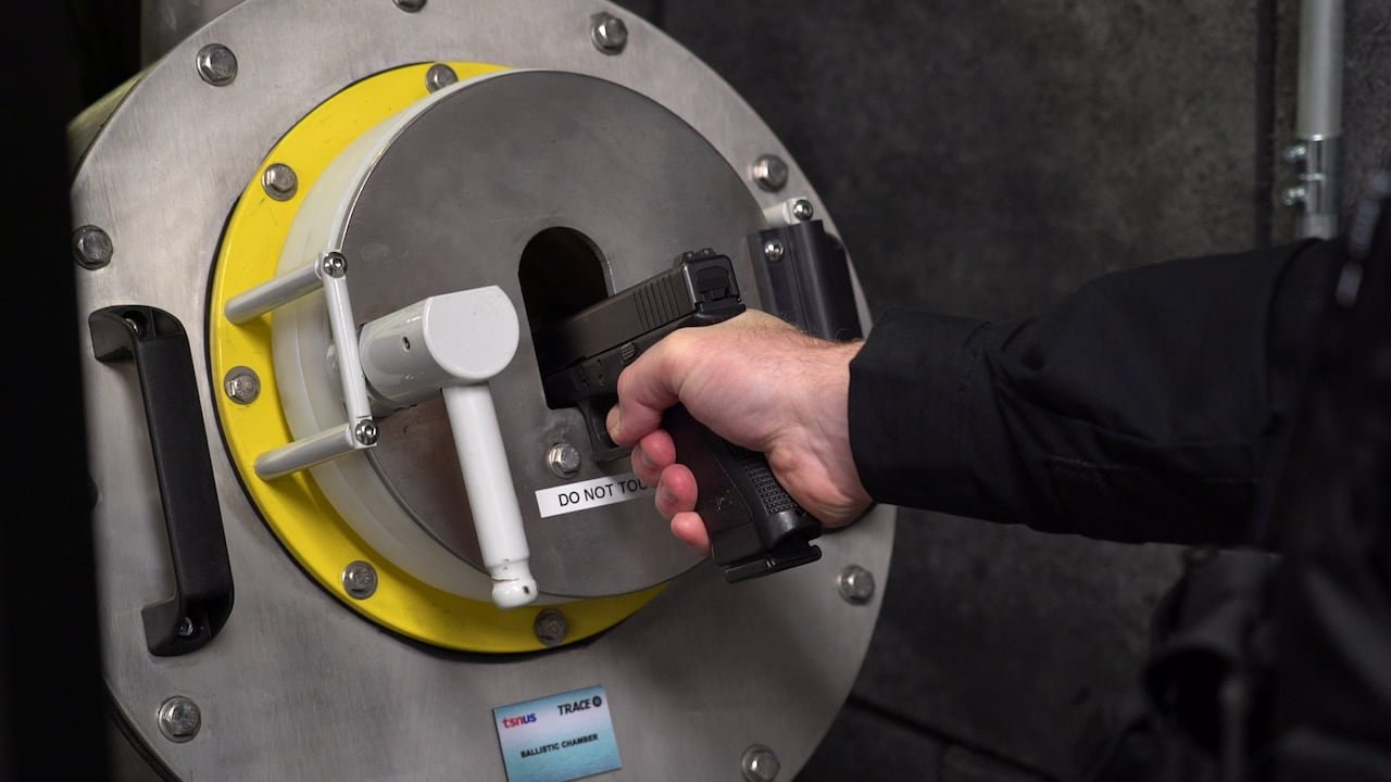 Walsh prepares to fire a Glock handgun into the ballistics chamber used to document the gun's fingerprint.