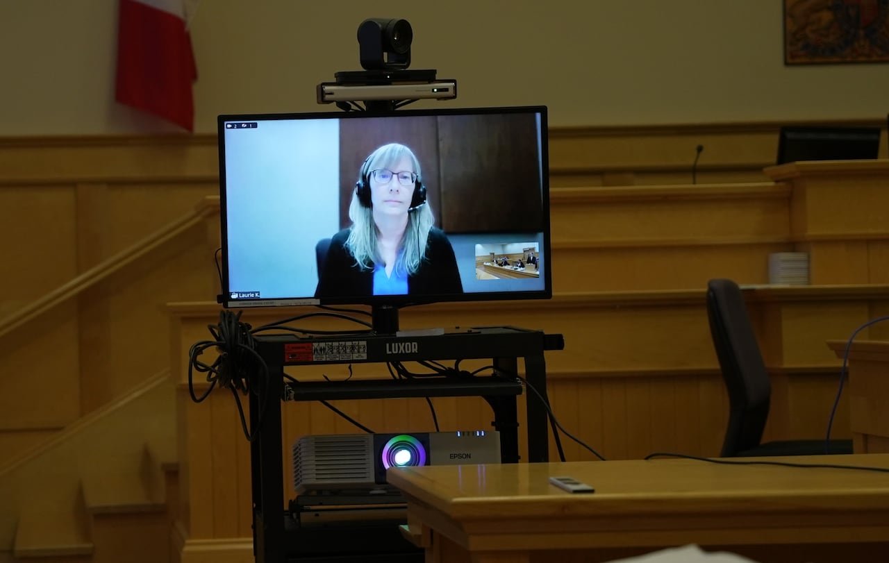 default-214 A courtroom setup with a TV and projector showing a woman on a Zoom call.