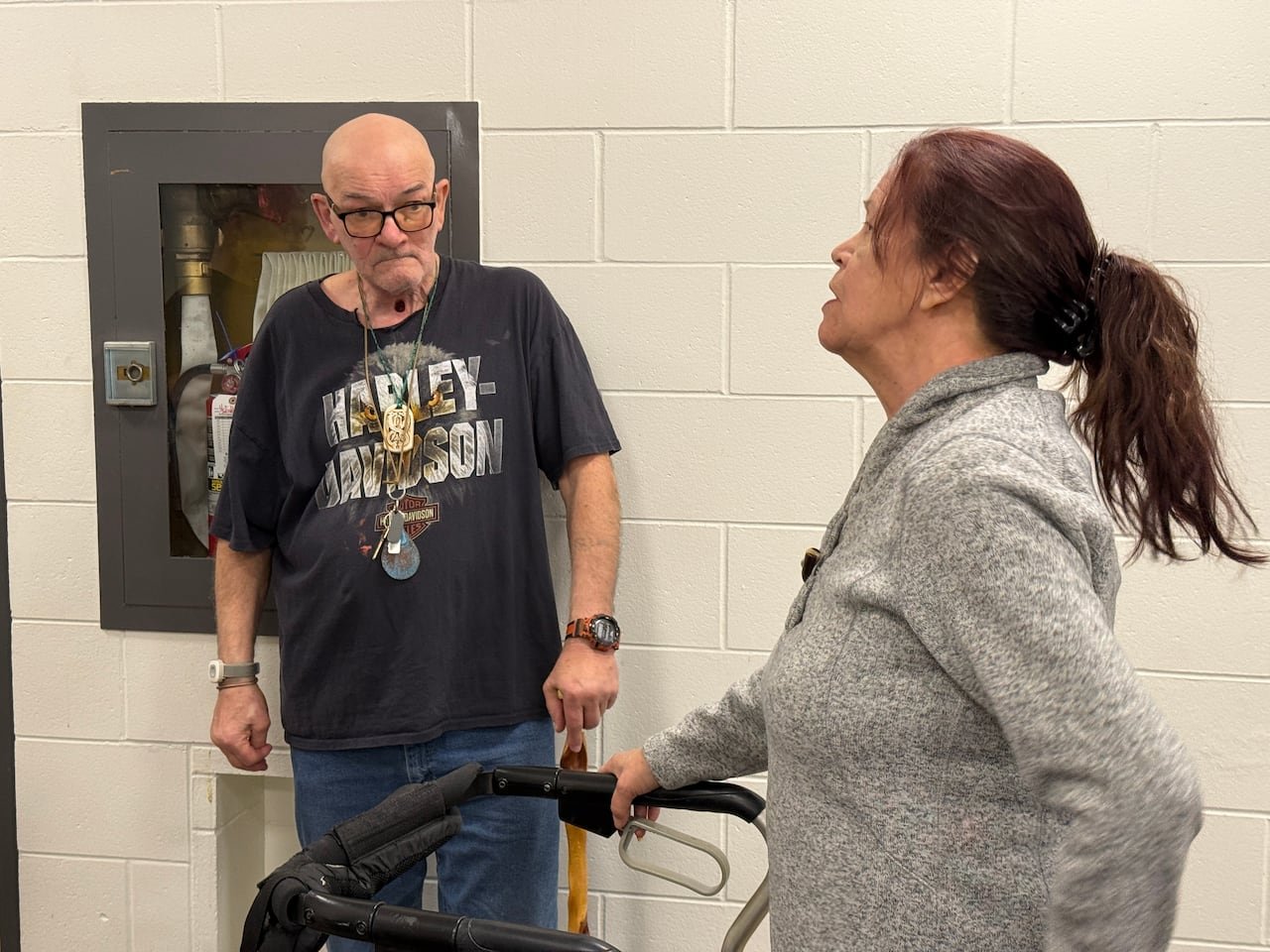 default-434 A man wearing a black Harley Davidson using a cane talks with a woman who uses a walker