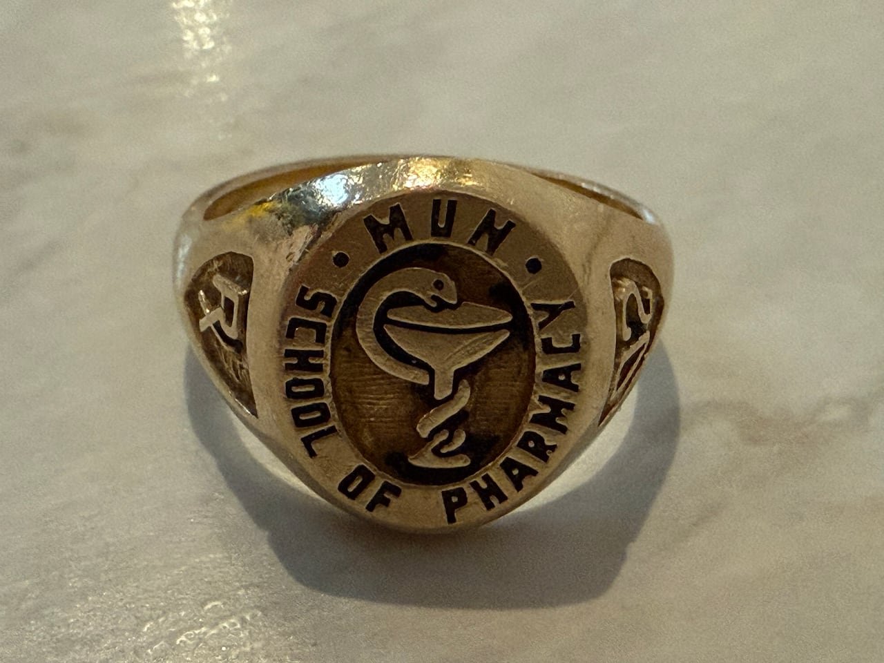 default-15 A golden ring engraved with a pharmacist's crest.
