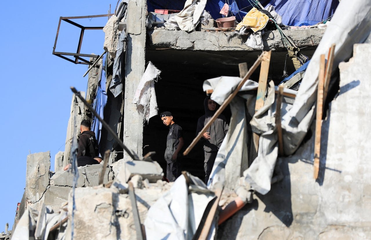 Several individuals inspecting damage at the site of an Israeli strike in Gaza City.