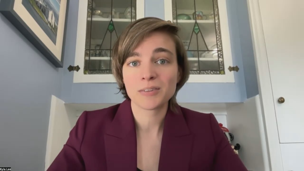 Vancouver-based criminal lawyer Kyla Lee sitting down with a maroon jacket on.