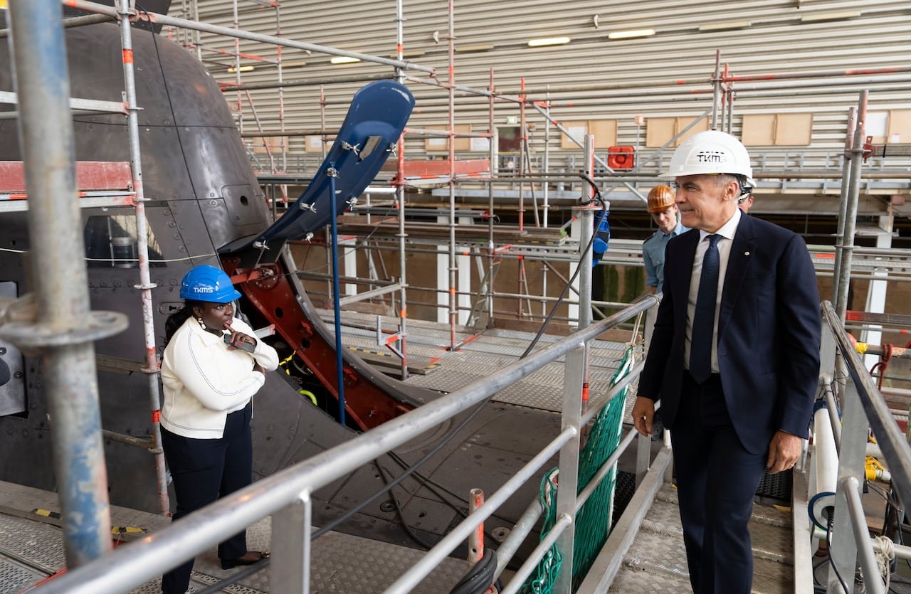default-1002 A man in a suit and a hard hat looking at a submarine propeller.