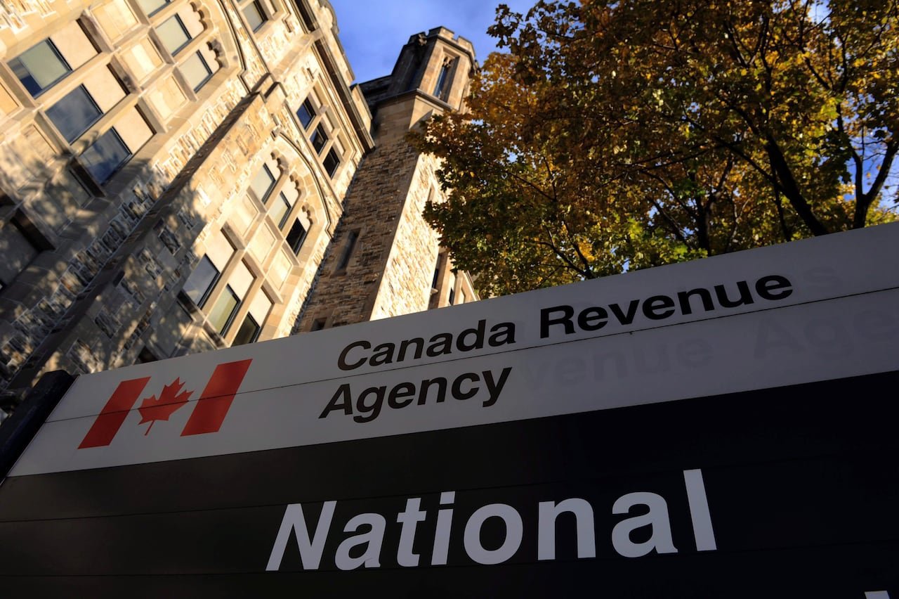 A sign saying Canada Revenue Agency sits in front of a large stone building.