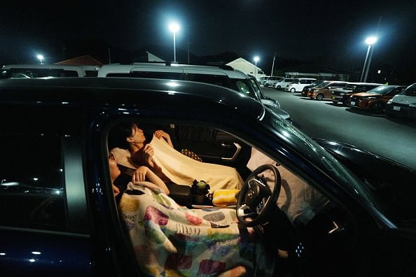 default-160 A man and a woman lie in their car seats covered with blankets.