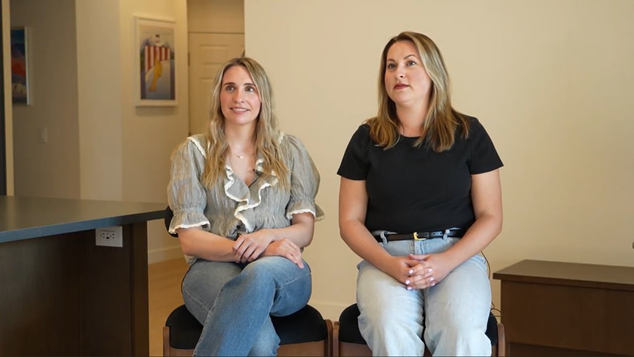 Two Caucasian women are sitting in a well-lit condo.